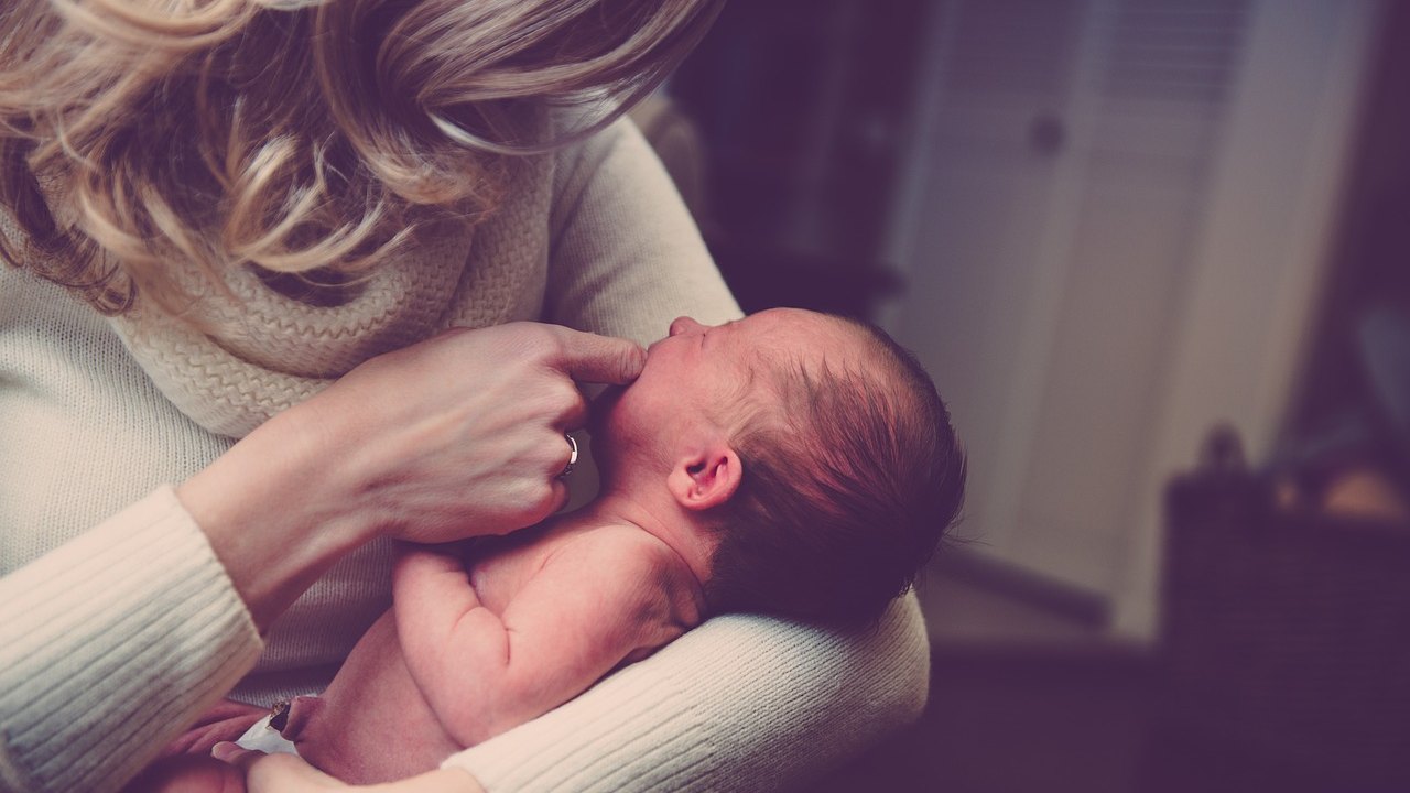 mother holding newborn baby hospital bed