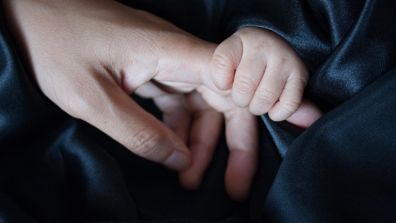 mother holding newborn baby hands